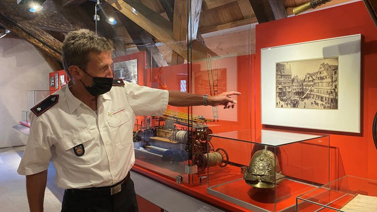 Feuerwehrmann Bernd Gugel zeigt auf die Ausstellungsstücke im Stadtmuseum in Tübingen. (Foto: SWR)
