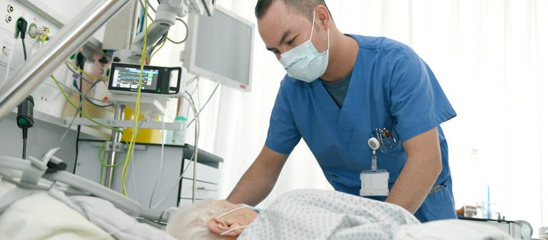 Ein Pfleger steht am Bett einer älteren Patientin in der Uniklinik Tübingen (Foto: Universitätsklinikum Tübingen/Britt Moulien)