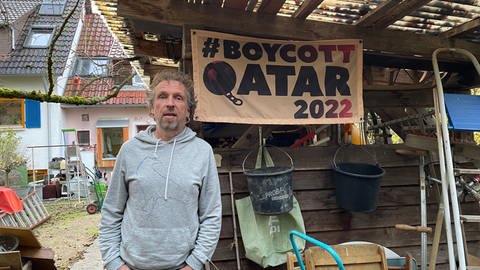 Christoph Leupolz vor einem Banner mit der Aufschrift: Boycott Qatar 2022 (Foto: SWR)