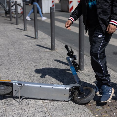 Ein Passant schiebt auf einem Gehweg einen E-Scooter zur Seite (Foto: dpa picture alliance, Hannes P. Albert)