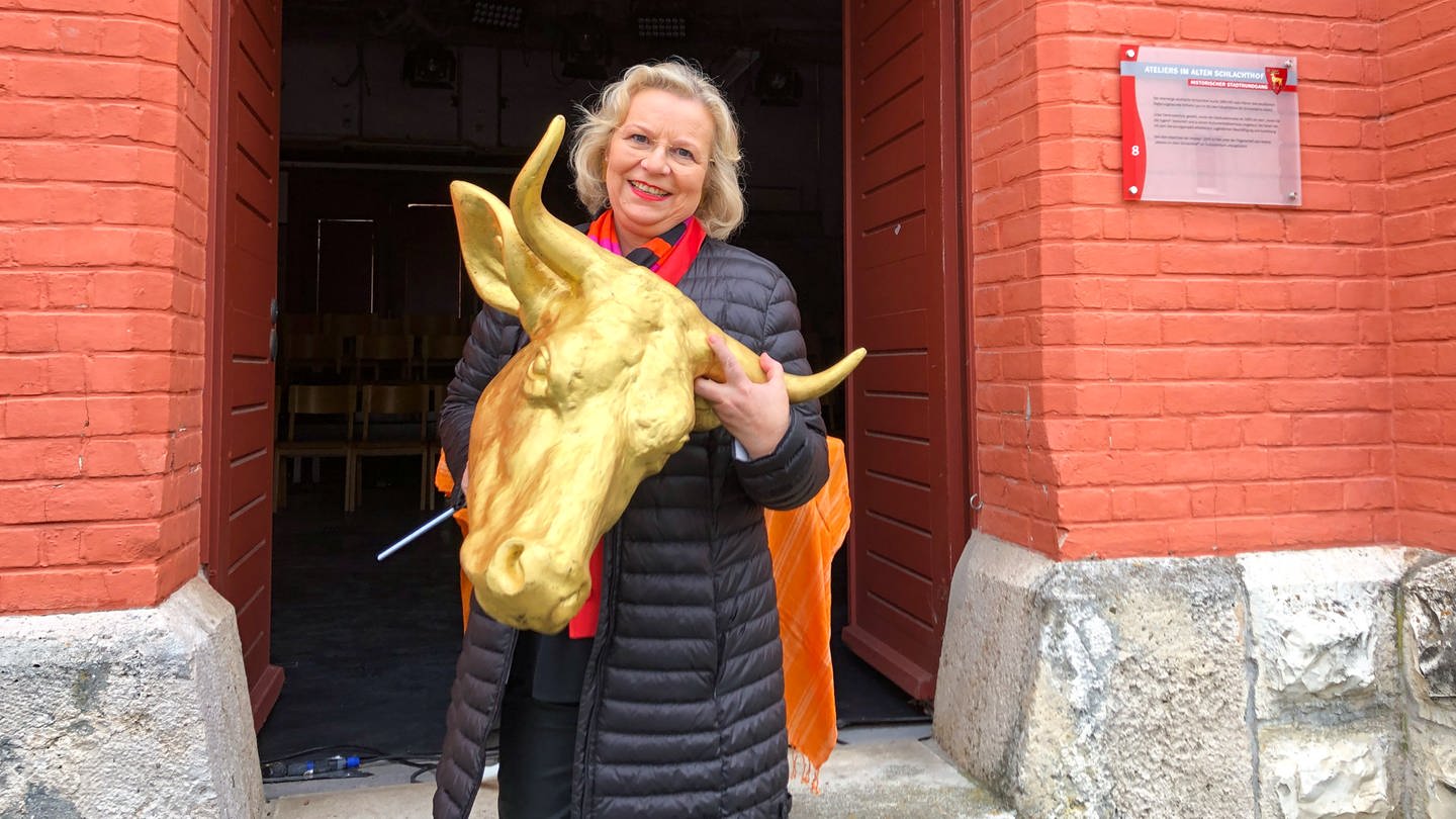 Daniela Lorch übergibt den goldenen Kuhschädel an die Ateliers im Alten Schlachthof Sigmaringen. Es ist eine Replik, ein Duplikat des Kuhschädels, der bis 2021 über dem eingang hing und bei Bauarbeiten abhanden gekommen ist. (Foto: SWR, Anne Schmidt)