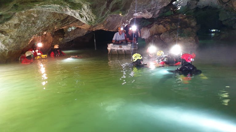 Ministerpräsident Kretschmann und Innenminister Strobl sitzen im Boot in der Wimsener Höhle und bekommen dort einen Höhlenrettungseinsatz gezeigt. (Foto: SWR, Christoph Necker)