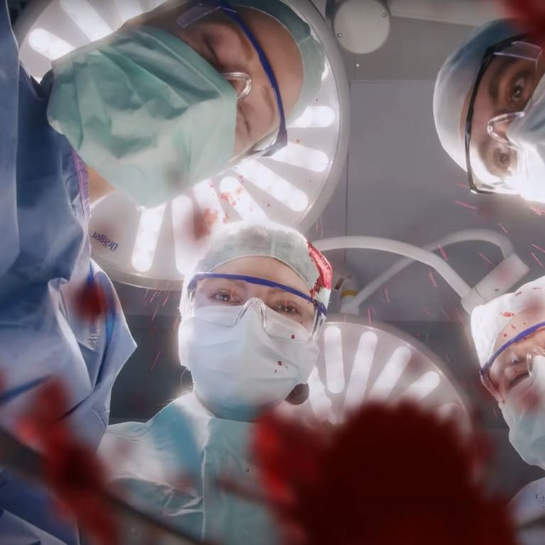 Die Uniklinik Tübingen wirbt mit einem witzigen Video um Personal. Der Screenshot zeigt Ärzte im OP. Sie operieren gerade. Es spritzt Blut. (Foto: SWR)