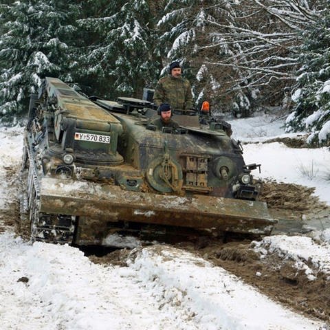 Ein Panzer mit zwei Soldaten rollt durch eine Kuhle aus Schnee und Matsch. (Foto: Joachim Lenk)
