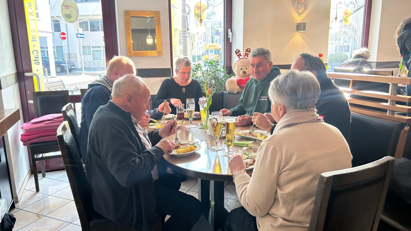 Man sieht einen runden Tisch mit zwei Frauen und vier Männern. Sie essen in einem Restaurant. Auf dem Tisch steht Essen und Trinken. (Foto: SWR)