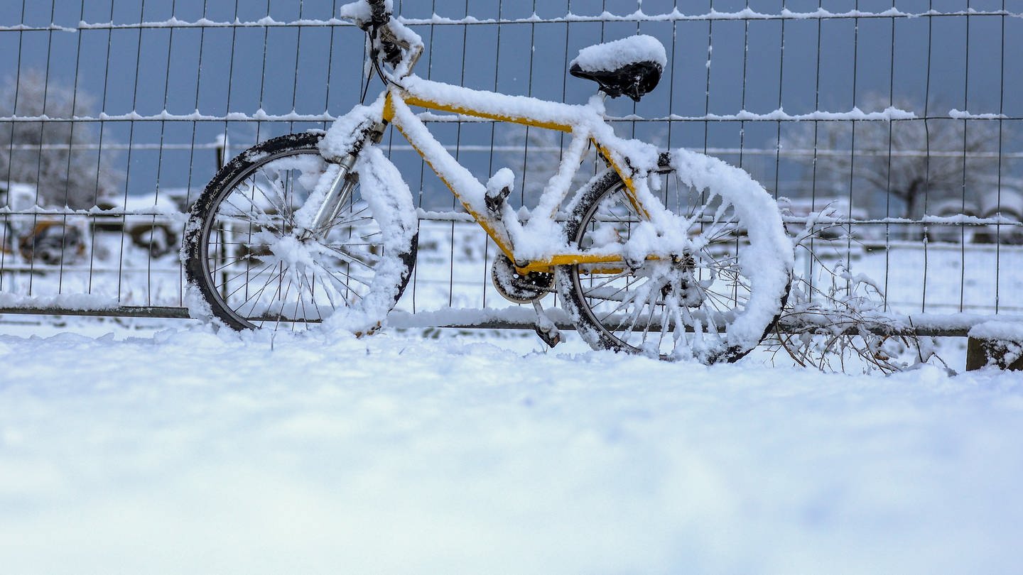 Ein mit Schnee bedecktes Fahrrad lehnt am Morgen bei Ittenhausen auf der Schwäbischen Alb an einem Zaun (Foto: dpa Bildfunk, picture alliance/dpa | Thomas Warnack)