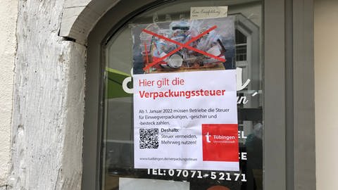 Ein Plakat der stadt Tübingen, angebracht auf einem Schaufenster, mit der Aufschrift "Hier gilt die Verpackungssteuer" (Foto: SWR, Stefanie Assenheimer)