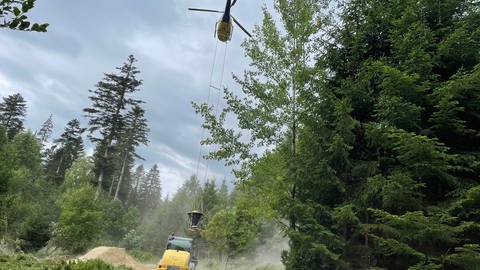Ein Hubschrauber lässt sich mit Kalk vom Boden beladen (Foto: SWR, Sarah Beschorner)