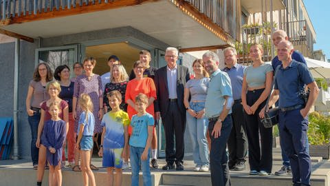BW-Ministerpräsident Winfried Kretschmann und Tübingens OB Boris Palmer inmitten einer Gruppe von Menschen bei einer gemeinsamen Besichtigung des Wohnviertels bei der alten Egeria.