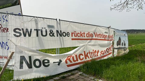 Mehrere Plakate gegen Windkraft hängen an einem Bauzaun in Starzach. Darauf werden die Stadtwerke Tübingen und Bürgermeister Thomas Noé aufgefordert, Verträge zu einem geplanten Windpark herauszurücken oder zurückzutreten. (Foto: SWR, Tobias Faißt)