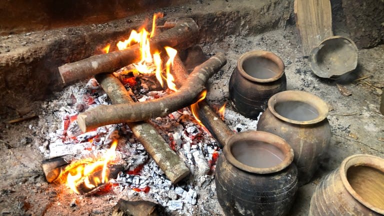Neben einem Feuer stehen Tontöpfe mit Wasser gefüllt (Foto: SWR)
