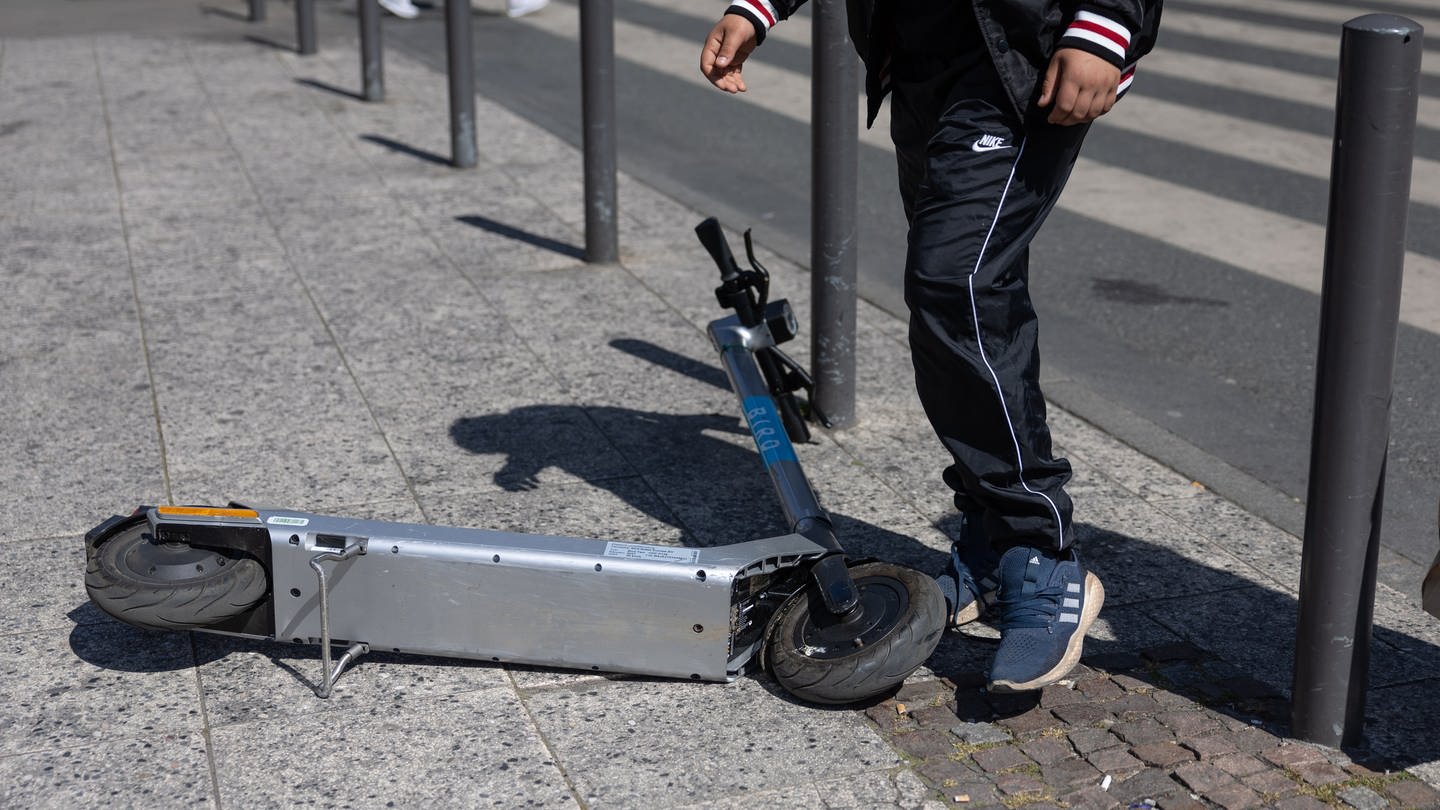 Ein Passant schiebt auf einem Gehweg einen E-Scooter zur Seite (Foto: dpa picture alliance, Hannes P. Albert)