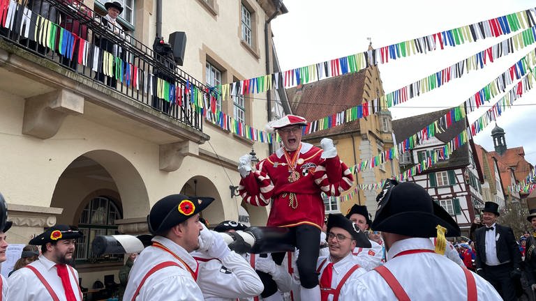 Der Sigmaringer Bürgermeister, der von mehreren jungen Männern in Tracht auf einer gepolsterten Stange getragen wird, ballt rufend die Fäuste.  (Foto: SWR, Anna Priese)