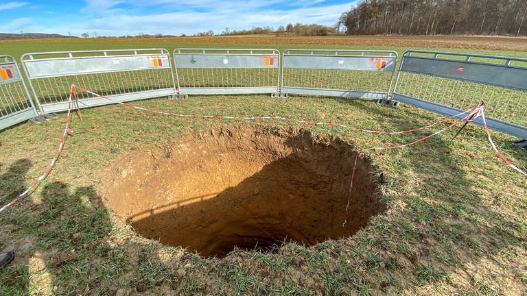 Auf einem Acker in der Nähe von Münsingen ist der Boden eingebrochen und hat eine Einsturzdoline von gut sieben Meter mit einem Durchmesser von drei Metern hinterlassen. Das Loch wurde mit Absperrzäunen gesichert.