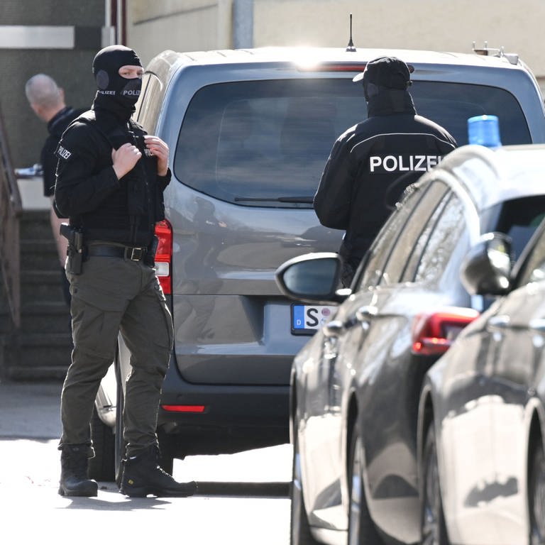 Einsatzkräfte stehen an Einsatzfahrzeugen. Bei einer Durchsuchung im Auftrag der Bundesanwaltschaft ist im baden-württembergischen Reutlingen ein Beamter eines Spezialeinsatzkommandos (SEK) durch einen Schuss verletzt worden.