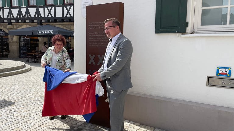 Die Frau des Ministerpräsidenten und der Bürgermeister von Pfullingen ziehen ein Tuch von der neuen Stele (Foto: SWR, Mia Zundel)