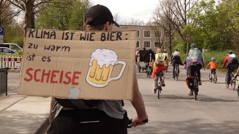 Schild auf dem Rücken eines Radfahrers: "Klima ist wie Bier - zu warm ist es scheise" (Foto: SWR, Harry Röhrle)