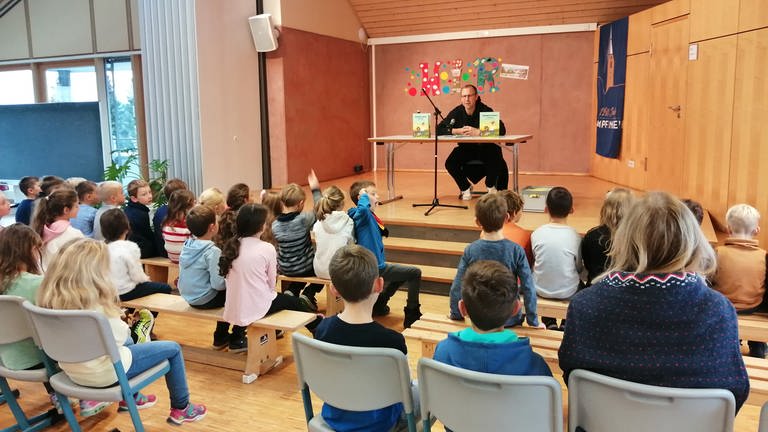 Empfingens Bürgermeister Ferdinand Truffner stellt Kinderbuch vor Erstklässlern an Grundschule vor. (Foto: SWR, Katharina Kregel)