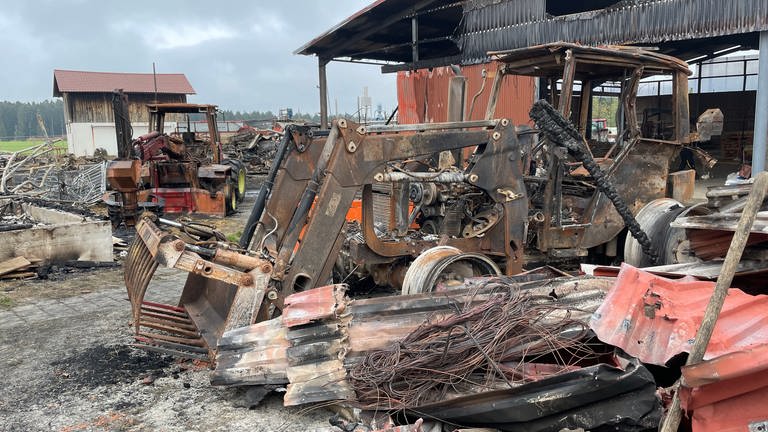 Das Metallgerippe eines ausgebrannten Traktors steht zwischen anderem Metallschrott