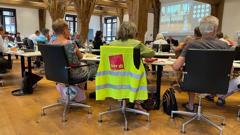 Eine Weste der Gewerkschaft ver.di hängt um einen Stuhl. Darauf sitzt eine Frau im Gemeinderat Tübingen. Sie ist Mitglied des Gemeinderats Tübingen. (Foto: SWR, Ingemar Koerner)