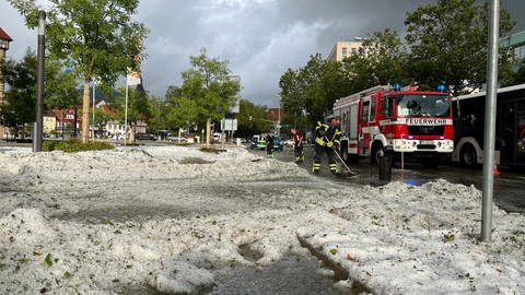 Einsatzkräfte der Feuerwehr beseitigen in der Reutlinger Innenstadt Berge von Hagelkörnern.