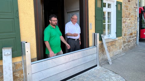 Der Reutlinger OB Thomas Keck und Bezirksbürgermeister Friedemann Rupp haben einen Teil des Hochwasserschutzes an der Tür des Rathauses in Betzingen eingebaut (Foto: SWR, Christoph Necker)