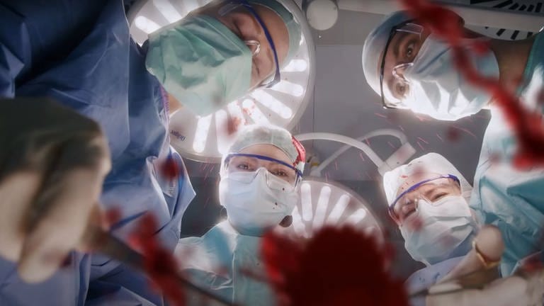 Die Uniklinik Tübingen wirbt mit einem witzigen Video um Personal. Der Screenshot zeigt Ärzte im OP. Sie operieren gerade. Es spritzt Blut. (Foto: SWR)