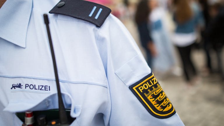 Schulterausschnitt eines Polizeibeamten bei der Streife, sichtbar sind Funkgerät, Schulterklappe und das BW-Wappen am Oberarm. (Foto: dpa Bildfunk, Christoph Schmidt)