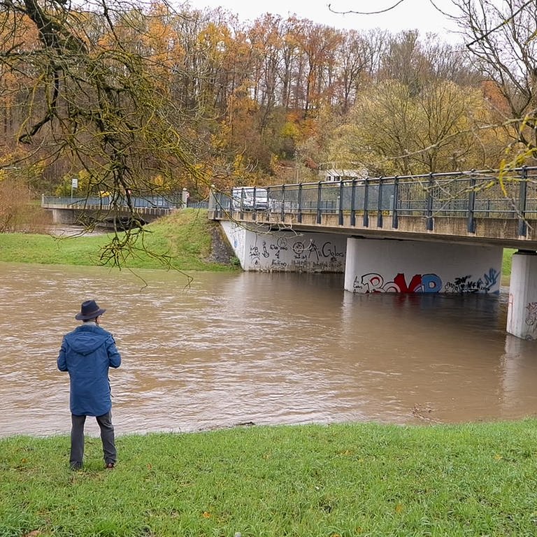 Ein Mann beobachtet den überfluteten Neckar vom Ufer aus.
