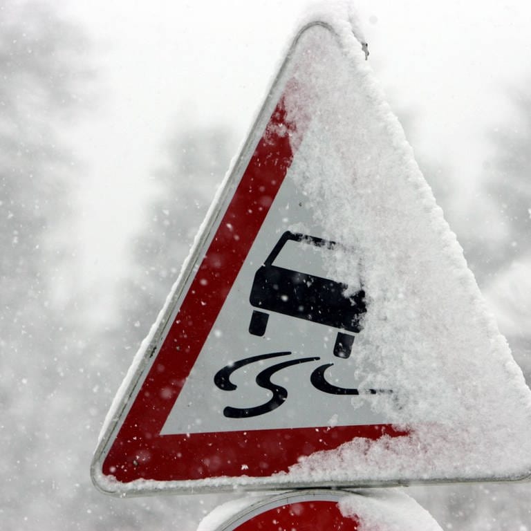 Ein schneebedecktes Verkehrsschild warnt vor Glätte. (Foto: picturealliance/dpa/Frederico Gambarini)