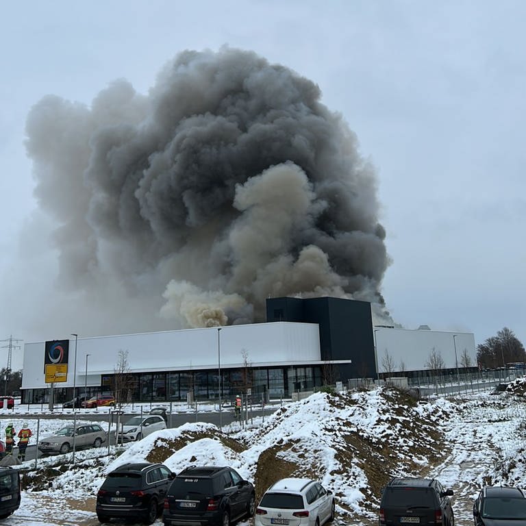 Über dem weißen Industriebau in Meßkirch hängen dichte, schwarze Rauchwolken. 