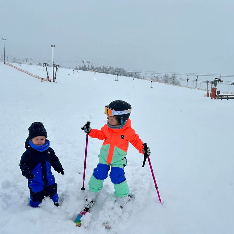 Zwei Kinder im Schnee, eines auf Skiern, im Hintergrund ein Skilift (Foto: SWR, Anne Schmidt)