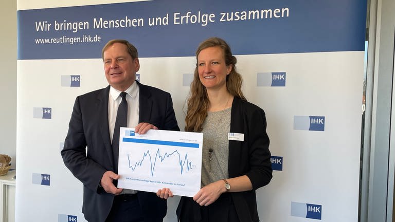 IHK-Hauptgeschäftsführer Wolfgang Epp und Antonia Hettinger, Leiterin regionale Wirtschaftspolitik halten ein Schaubild mit einer Konjunkturkurve in die Kamera.  (Foto: SWR, Peter Binder)