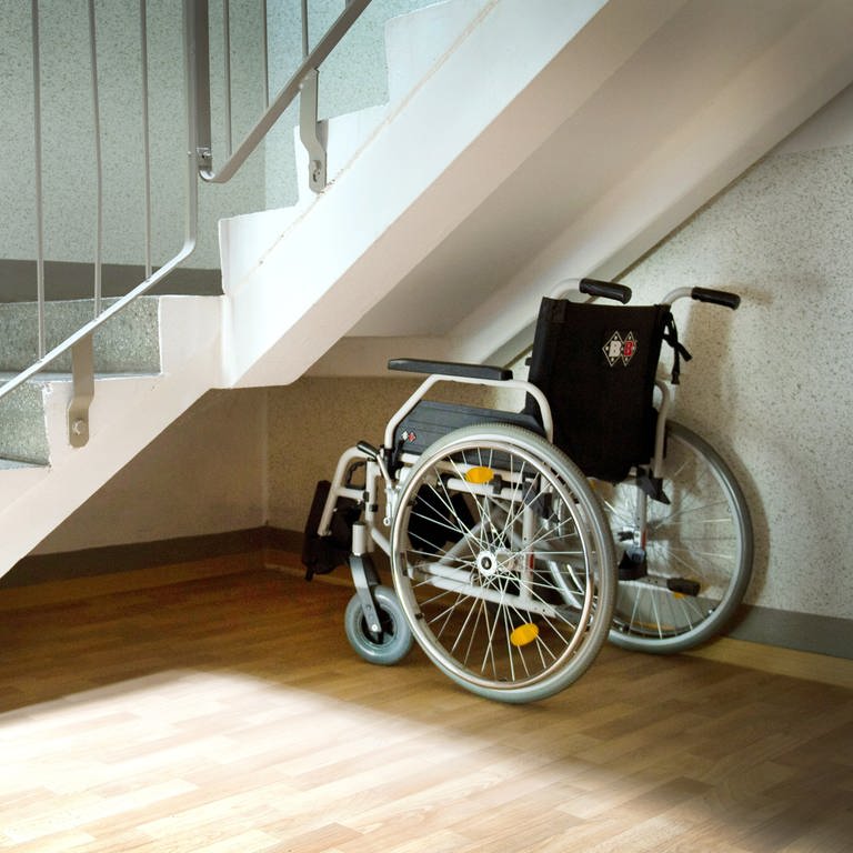 Symbolbild: Ein Rollstuhl steht neben einer Treppe.