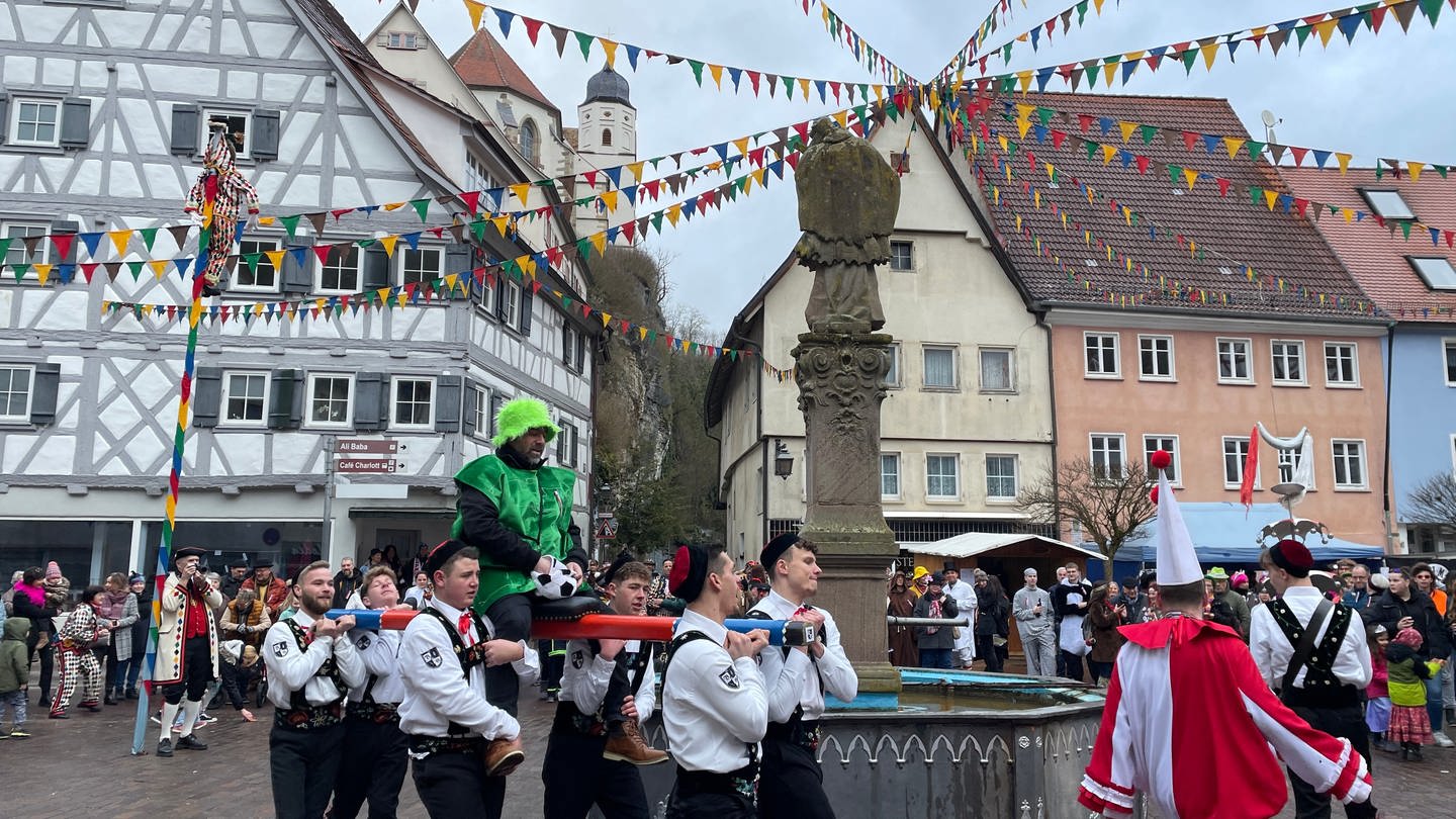 Die Bräutelgesellen tragen einen Neubürger auf einer Stange um den Marktbrunnen in Haigerloch (Zollernalbkreis). (Foto: SWR)