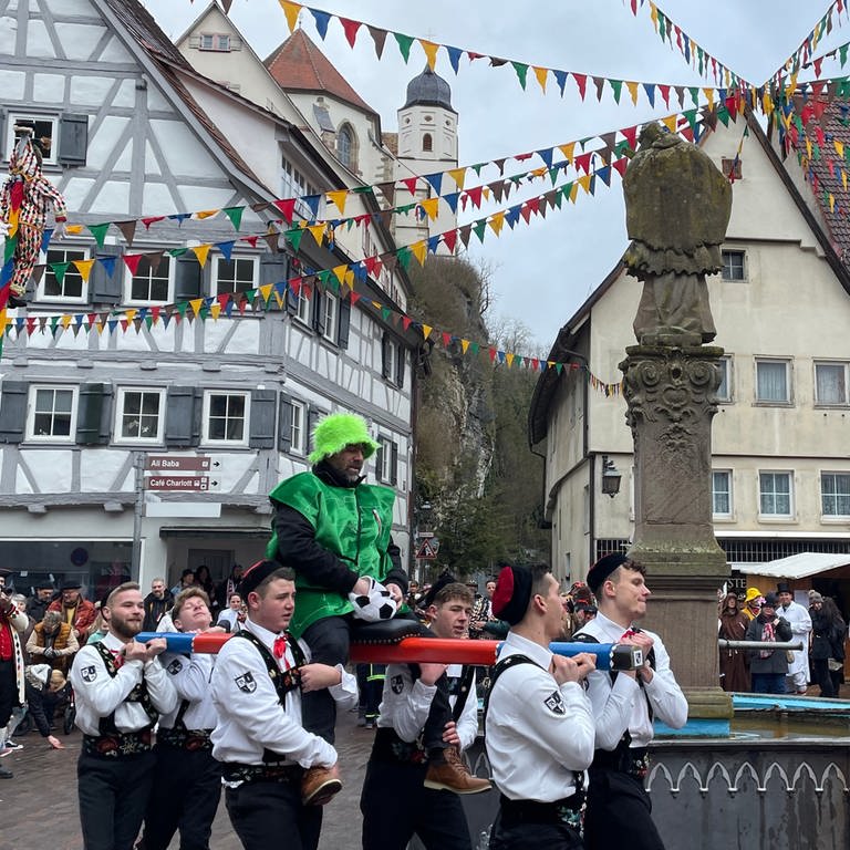 Die Bräutelgesellen tragen einen Neubürger auf einer Stange um den Marktbrunnen in Haigerloch (Zollernalbkreis).  (Foto: SWR)