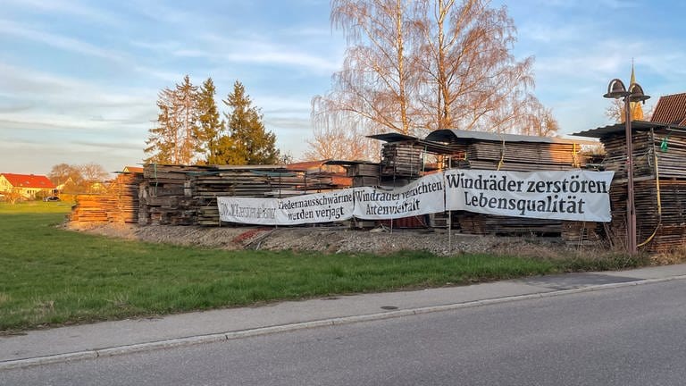 Ein Protestplakat gegen Windräder hängt neben einem Holzlager in Starzach, Kreis Tübingen. In Starzach wird ein Windpark mit sieben Windrädern geplant. (Foto: SWR, Ingemar Koerner)