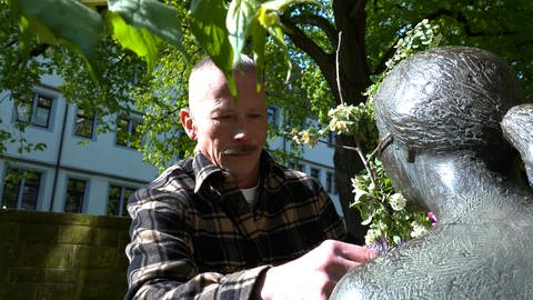 Dithelm Marx tauscht bei einer Statue in einer Tübinger Altstadt die Blumen aus. Das macht er jede Woche.