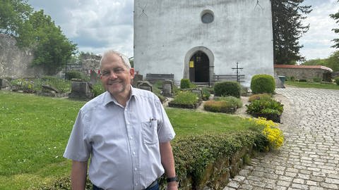 Günter Braun ist Vorsitzender des Komitees zur Erhaltung der Kirche in Gruorn, er steht vor der wiederaufgebauten Kirche.