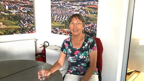 Elfriede Thierfelder sitzt mit einem Glas Wasser in der Hand an einem Tisch (Foto: SWR)