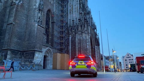 Ulmer Münster in der Morgendämmerung. Ein Polizeiauto steht vor dem Hauptportal (Foto: SWR, Hannah Schulze)