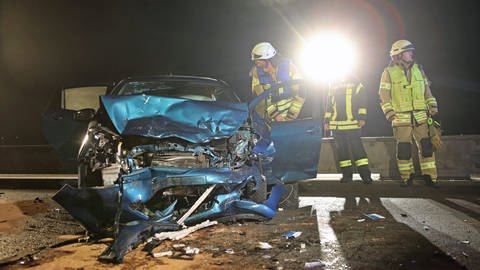 Einsatzkräfte nachts an einem Unfallort vor einem total demolierten Auto (Foto: Ralf Zwiebler)