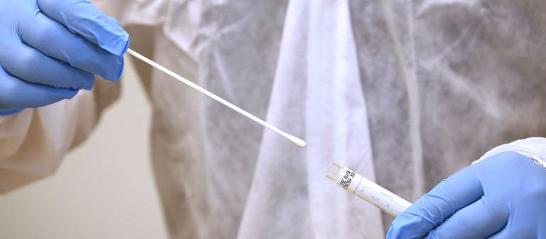 Ein Arzt hält in einer Hausarztpraxis einen Tupfer mit dem ein Abstrich für einen Coronatest gemacht wird. (Foto: dpa Bildfunk, picture alliance/dpa | Karl-Josef Hildenbrand)