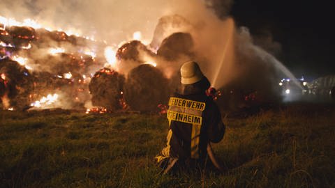 Ein Feuerwehrmann versucht brennende Heuballen in Steinheim im Albuch zu löschen. (Foto: onw-images / Dennis Straub)