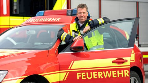 Ein Mann in Feuerwehr-Uniform steht vor einem Feuerwehr-Pkw (Foto: Pressestelle, Stadt Ulm, Feuerwehr Ulm)