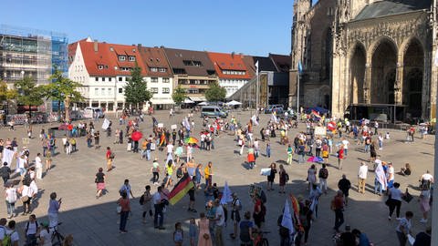 Menschen mit Transparenten auf dem Ulmer Münsterplatz bei der "Querdenker"-Kundgebung (Foto: SWR, Martin Miecznik)