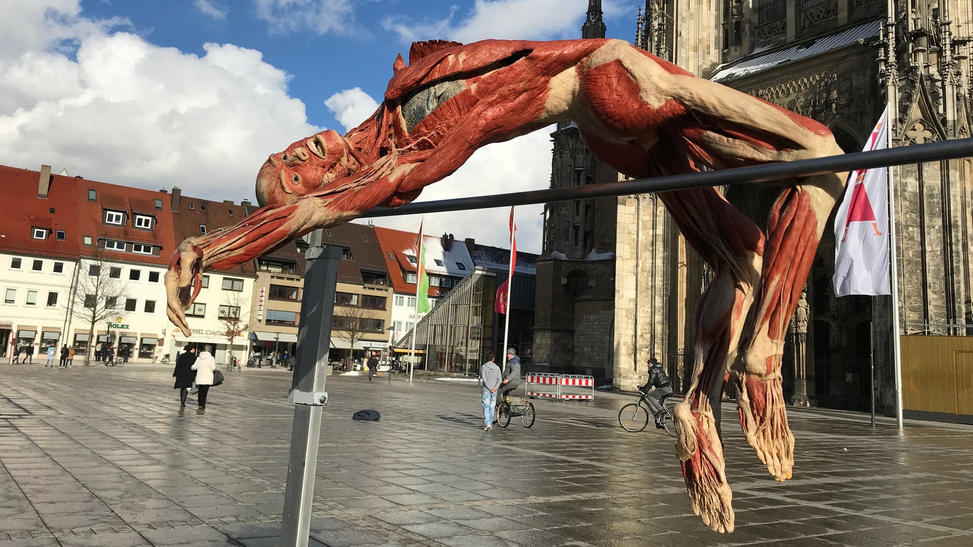 Ein Exponat der Ausstellung "Körperwelten" als Stabhochspringer auf einem großen Platz vor einer Kirche (Foto: SWR, Timo Staudacher)