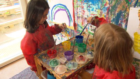 Kinder spielen in einer Einrichtung mit Farben.  (Foto: SWR)