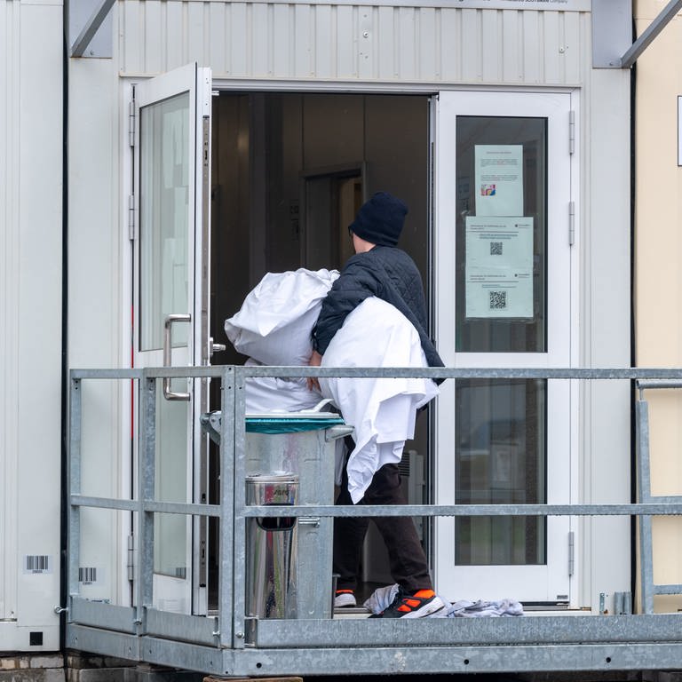 Ein Mann bringt Bettwäsche in einen Container. In Blaustein Herrlingen sollen in einer solchen Unterkunft 100 bis 200 Geflüchtete Platz finden. (Symbolbild) (Foto: dpa Bildfunk, picture alliance/dpa | Harald Tittel (Symbolbild))