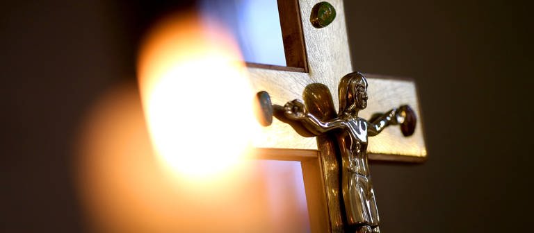 Kruzifix vor einer Kerze. Die Diözese RottenburgStuttgart muss sich mit Missbrauchsvorwürfen auseinandersetzen. (Foto: dpa Bildfunk, picture alliance dpa-Zentralbild  Ronny Hartmann)